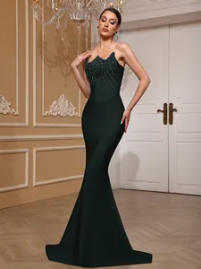 Full-length view of dark green strapless mermaid evening gown with crystal tassels.