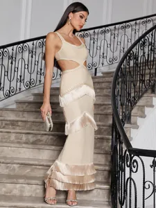 Detail of tiered tassels and waist cut-out on a beige knitted bandage maxi dress