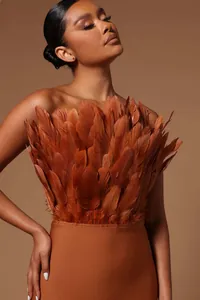 Close-up of elegant brown strapless midi dress featuring dramatic feather bust detail