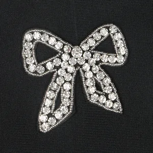 Detailed close-up view of a sparkling rhinestone bow on a black bandage party dress