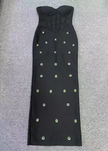 Full view of black strapless mermaid evening dress with green gemstone embellishments