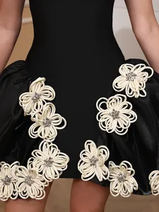Close-up of elegant 3D white ribbon flowers with crystal centers on a black bandage dress.