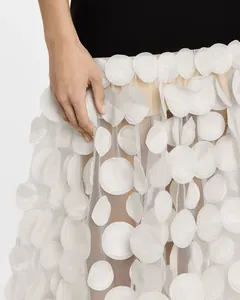 Zoom sur les détails des appliques florales en pétales blancs d'une robe de soirée.
