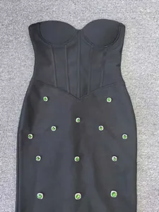 Detailed view of black bandage mermaid dress featuring elegant green gemstone embellishments.