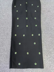 Close-up detail of black bandage dress featuring elegant green gemstone embellishments