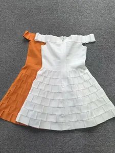 Detailed close-up of textured white and orange bandage mini dresses with zippers