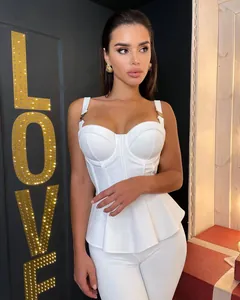 Detail showing white ribbed knit bandage top with metal buckle straps and white pants