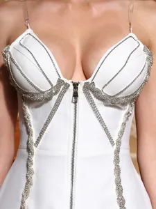 Close-up detail of white bodycon dress with sparkling rhinestone trim and front zipper.