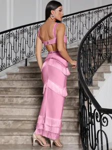 Back view detail of pink bandage crop top and maxi skirt with layered fringe tassels