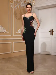 Elegante vestido largo bandage negro con detalles de joyas rojas y verdes laterales
