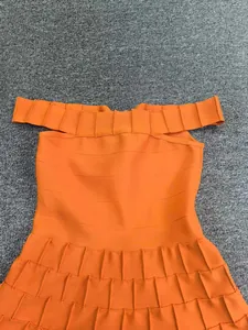Detailed view of orange bandage knit dress with pleated A-line skirt design