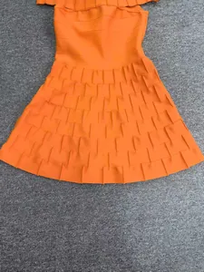 Close-up detail of the tiered ruffled hem and knit texture on this orange bandage dress