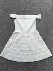 Detail view of the tiered pleated skirt on a white off-the-shoulder bandage dress