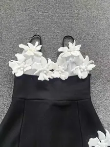 Détail d'une robe bandage noire ornée de grandes décorations florales blanches en 3D.
