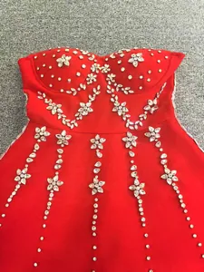 Detailed macro shot of a red bandage dress featuring intricate floral rhinestone beadwork.