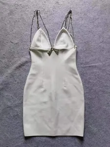 Elegante witte bodycon jurk met diamanten kettingbandjes en een strik van strass