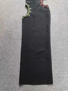 Detalle de vestido bandage negro con decoración asimétrica de piedras rojas y verdes