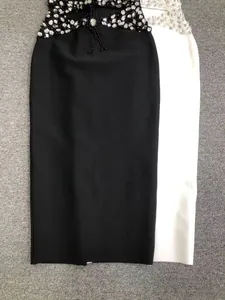 Close-up of elegant black and white bandage midi dresses with heavy rhinestone waist detail