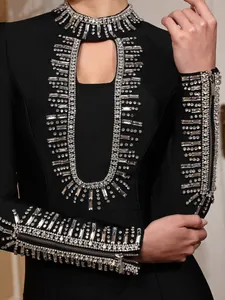 Close-up of heavy rhinestone beading and crystal detail on luxury black evening dress.