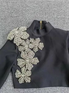 Detailed close-up of a black bandage top featuring sparkling crystal flower appliques