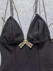 Detailopname van een zwarte feestjurk met strass bandjes en een strik detail.