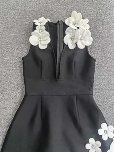 Close-up detail of black sleeveless bandage dress with 3D white flower beads and deep V-neck