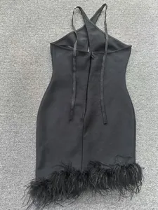 Gros plan d'une robe bandage noire dos nu avec une bordure en plumes luxueuse.
