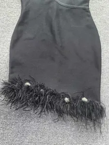 Gros plan détaillé de l'ourlet d'une robe bandage noire avec plumes et strass