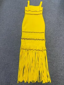 Detailed view of bright yellow bandage dress featuring gold sequins and long fringe tassels.