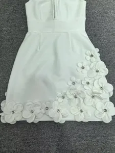 Detailed view of white bandage dress featuring intricate 3D floral and beadwork