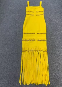 Detailed view of yellow bandage evening gown featuring intricate beading and long fringe tassels.