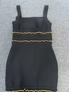 Close-up of gold bead accents and fringe details on a black bandage bodycon dress