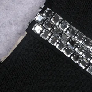Close-up detail of clear square rhinestones on black bandage fabric jumpsuit