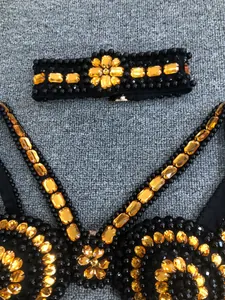 Detailed view of a black bandage evening dress with intricate amber rhinestone beadwork.