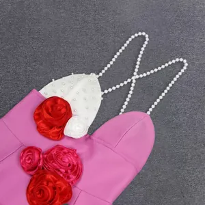 Detailed macro view of elegant pearl straps and red 3D rose appliques on pink bandage dress