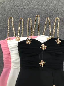 Detailansicht eleganter figurbetonter Kleider mit goldenen Ketten und Perlenkreuzen