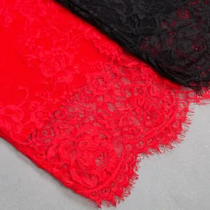 Close-up detail of exquisite red and black floral lace with delicate eyelash fringe edges.