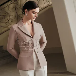 Vista dettagliata delle decorazioni in perle e strass sulla vita di un blazer beige