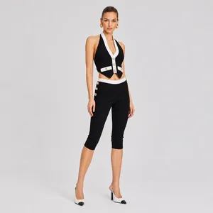 Elegant zwart-wit contrast haltertop en legging set met goudkleurige knoopdetails.
