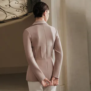 Dettaglio di un elegante blazer sciancrato in rosa cipria con retro plissettato.