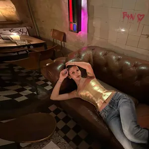 Sexy metallic gold corset crop top shown on a model reclining on a vintage leather sofa.