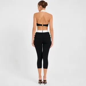 Achteraanzicht van contrasterende haltertopt en bandagebroek met gouden knoopdetails.