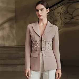 Primo piano dei lussuosi dettagli in perle e strass su un blazer rosa sciancrato