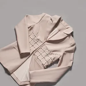 Primo piano delle decorazioni a griglia con perle e strass su elegante blazer beige