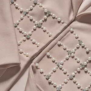 Dettaglio ravvicinato delle decorazioni in perle e strass su una giacca blazer bandage color nudo.