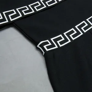 Primo piano di una tuta nera elegante con spalle scoperte e dettaglio greco bianco.
