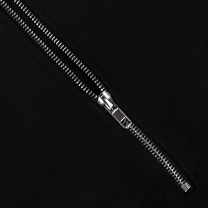 Detailed close-up of a smooth silver metal zipper on black ribbed jumpsuit fabric