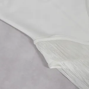 Macro view showing the intricate white fringe and tassel details on an elegant jumpsuit
