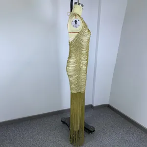 Side detail view of a gold fringe halter neck evening gown on a mannequin for party