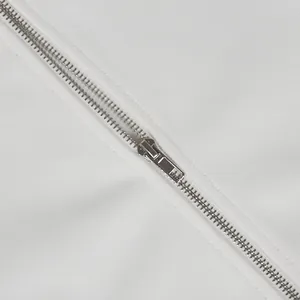 Detailed macro view of a smooth silver metal zipper on premium white jumpsuit fabric